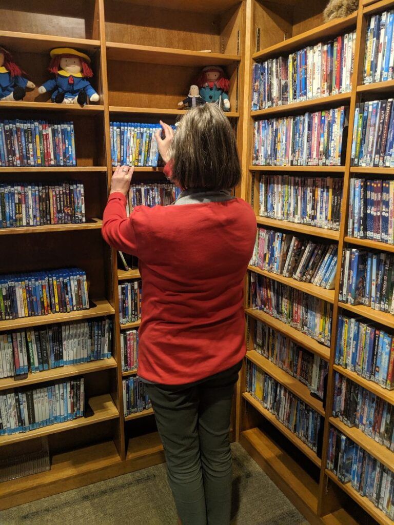 A Dunbar Free Library staff member shelving DVDs and Blu-rays in the library's media collection