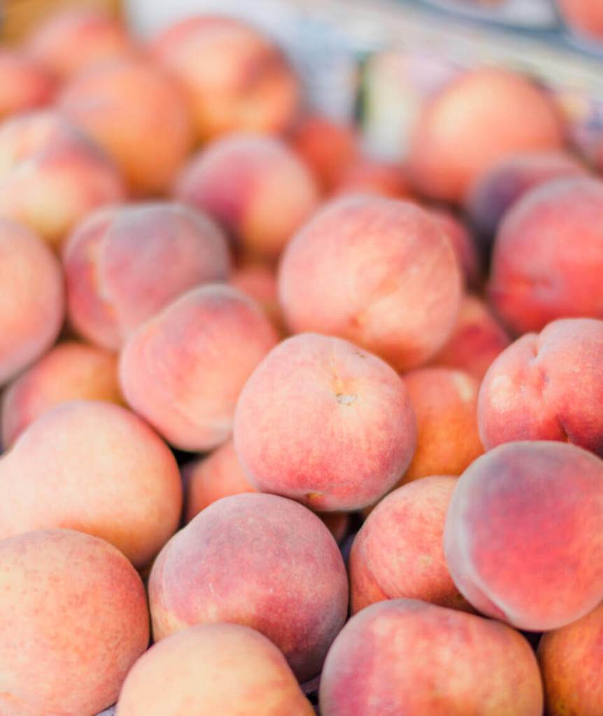 A heaping pile of fresh peaches at a farmers market